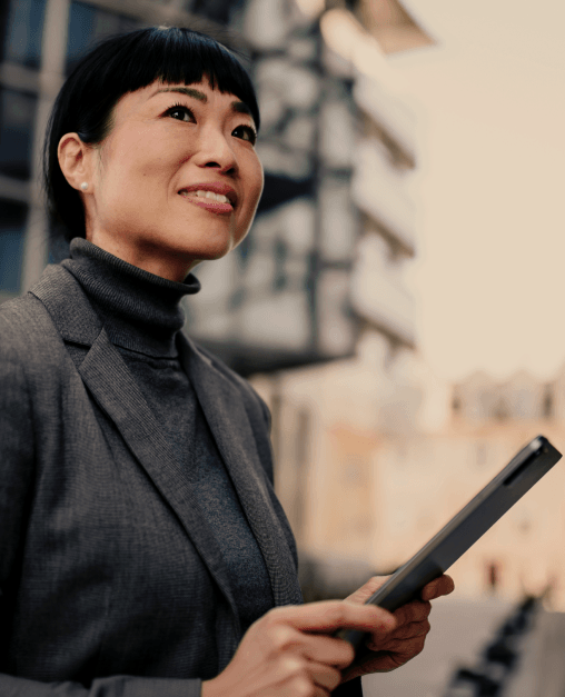 Why active investors switch and what banks can do A person in professional clothing standing outdoors in an urban environment, holding a digital tablet.