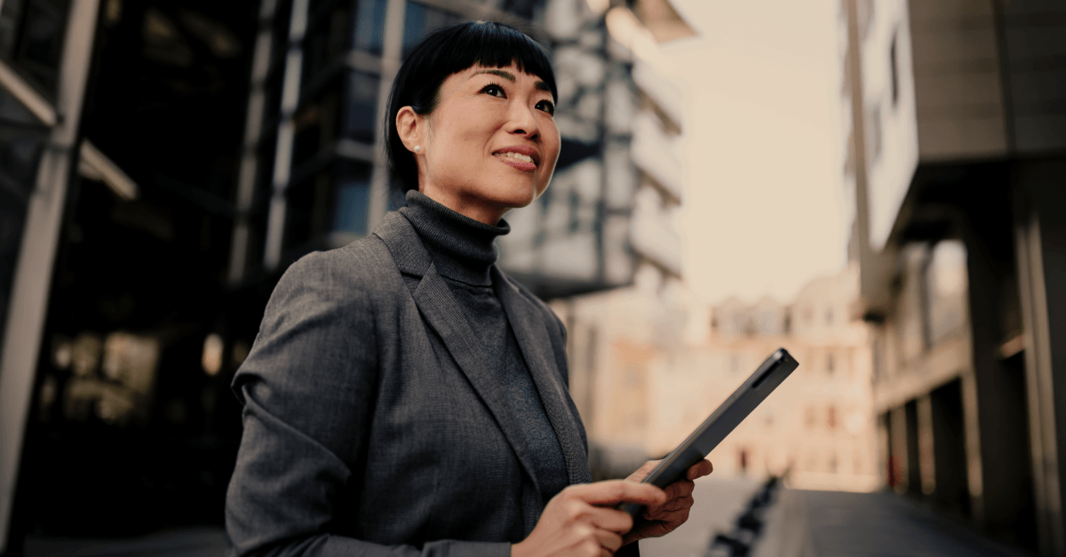 Engaged but restless: why highly active investors switch and how banks can keep them A person in professional clothing standing outdoors in an urban environment, holding a digital tablet.